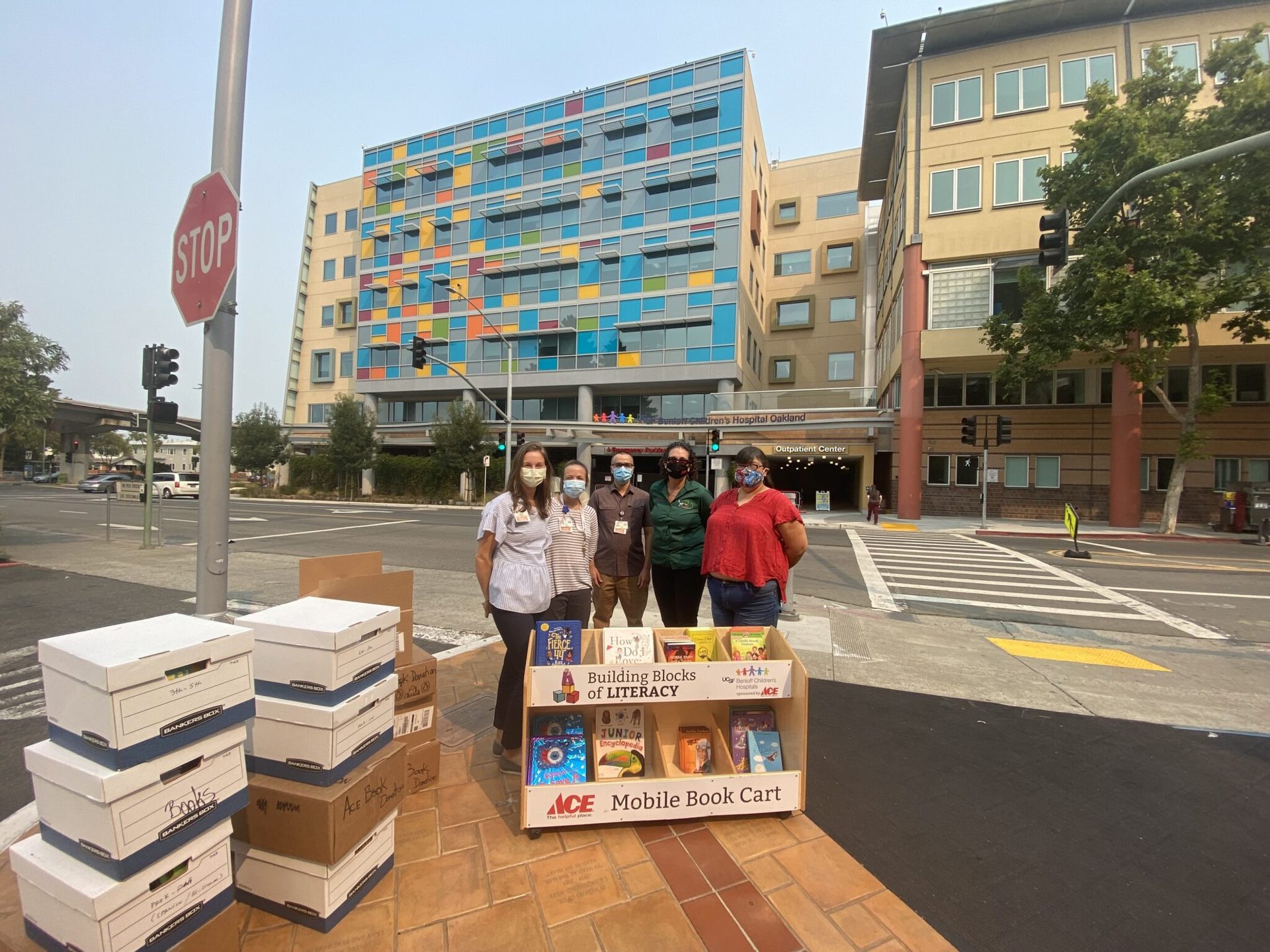 Team members with a mobile book cart and boxes of donated books